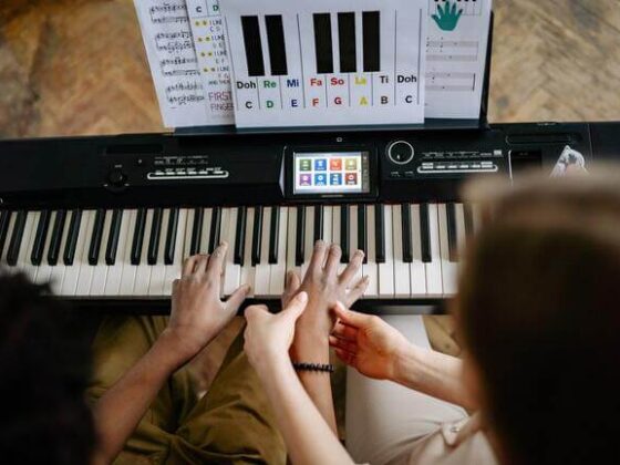 teacher and student are practicing from a piano book with letter notes
