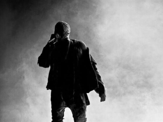 kanye west performing on stage in front of a grey hazy background