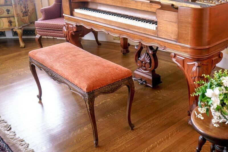a piano practice area with an orange piano bench cushion